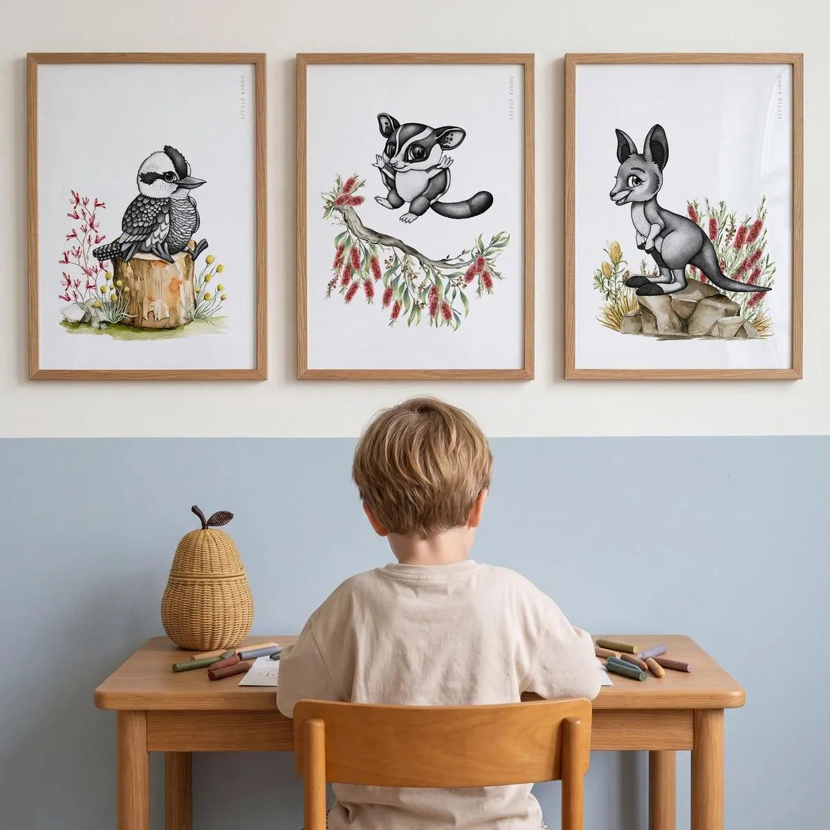 Set of 3 Australiana nursery prints—Kookaburra, Sugar Glider, and Kangaroo—styled above a child's wooden desk and chair.