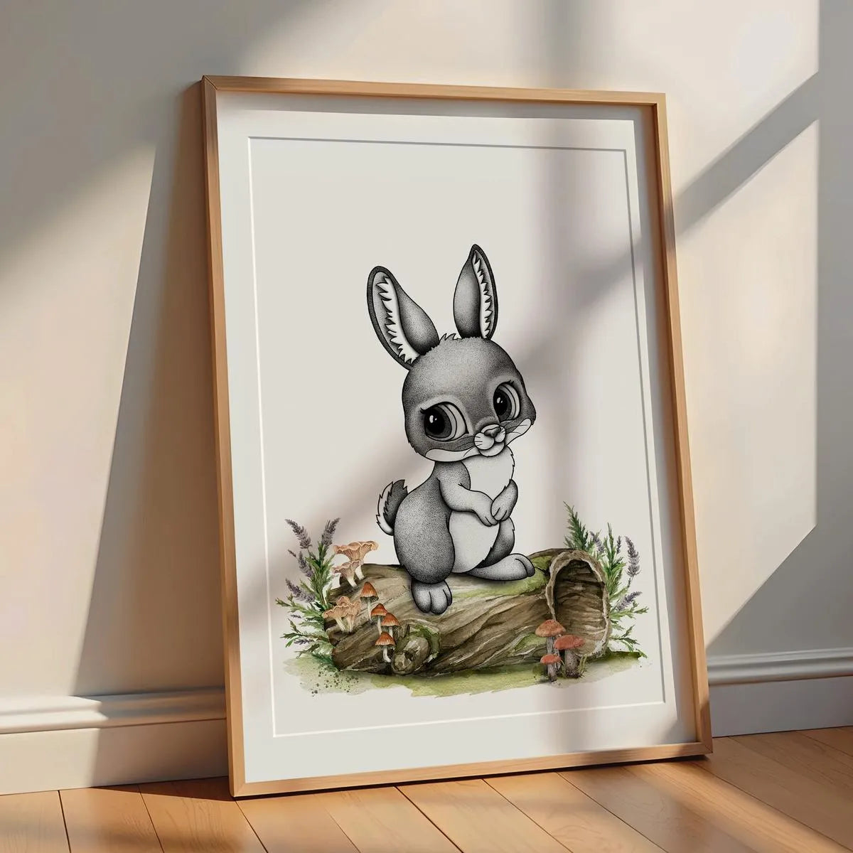 Minimalist bunny-rabbit illustration nursery print in an oak frame leaning against a white wall with soft natural sunlight.