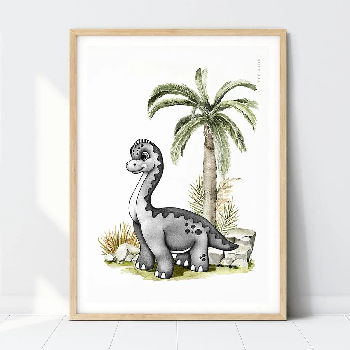 Hand-drawn baby Brachiosaurus nursery art print standing by a tall palm tree in a light wood frame, prehistoric dinosaur wall decor.
