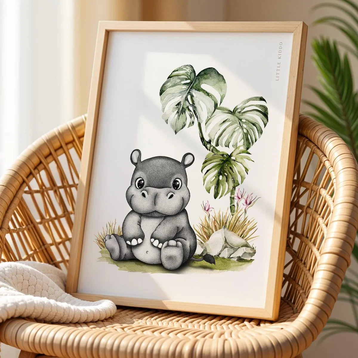 Cute hippo nursery poster displayed on a wicker chair, boho-style safari animal wall art for a modern neutral nursery.