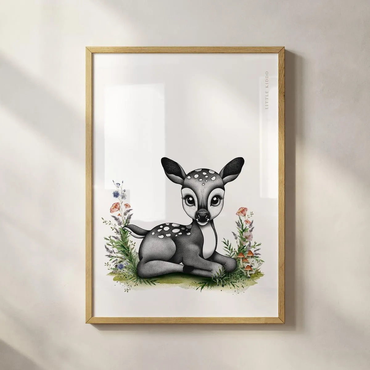 Minimalist woodland fawn art print in a light wood frame, artisanal forest animal wall hanging for a modern baby room.