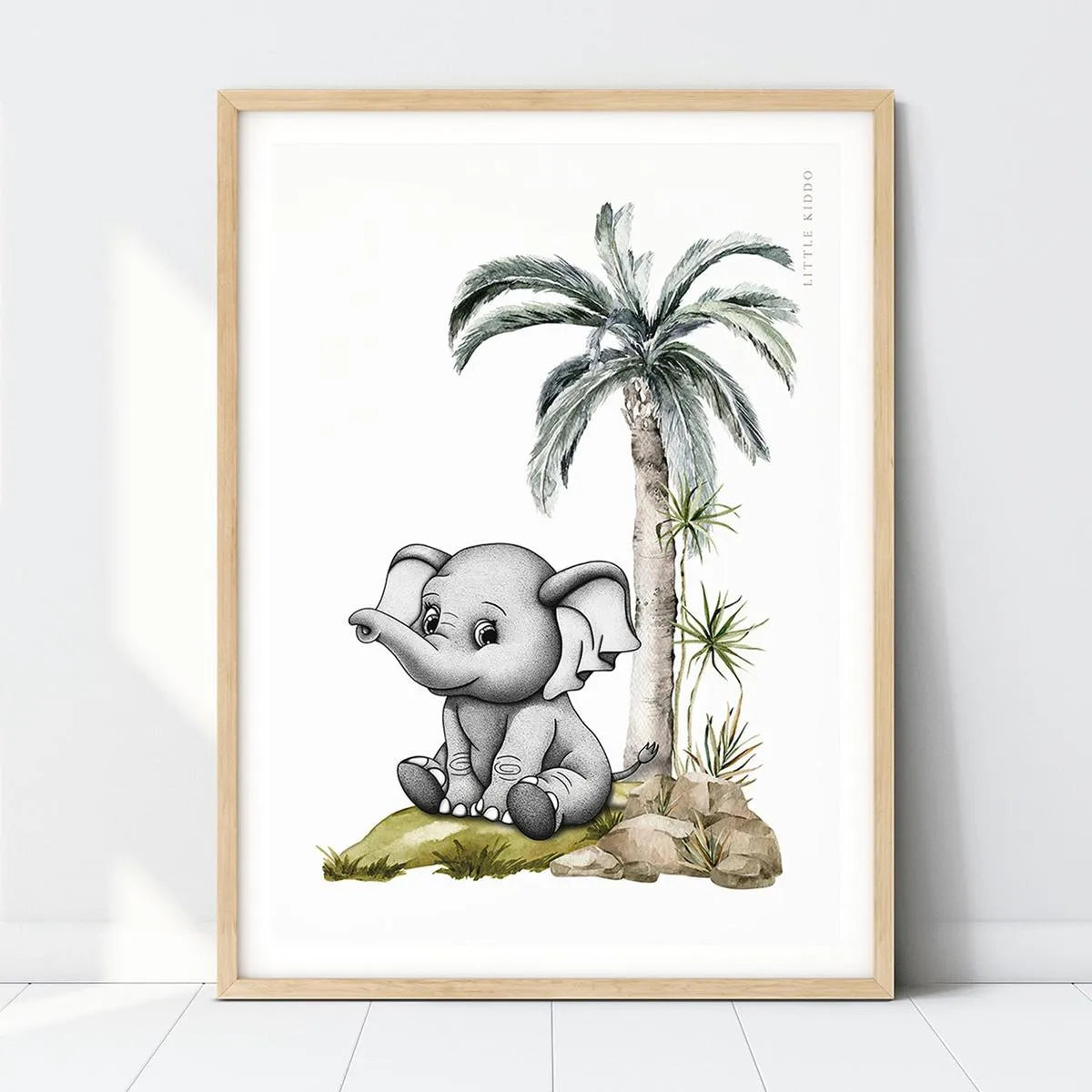 Baby elephant nursery art print featuring a hand-drawn elephant under a palm tree in a light wood frame, safari-themed wall decor.