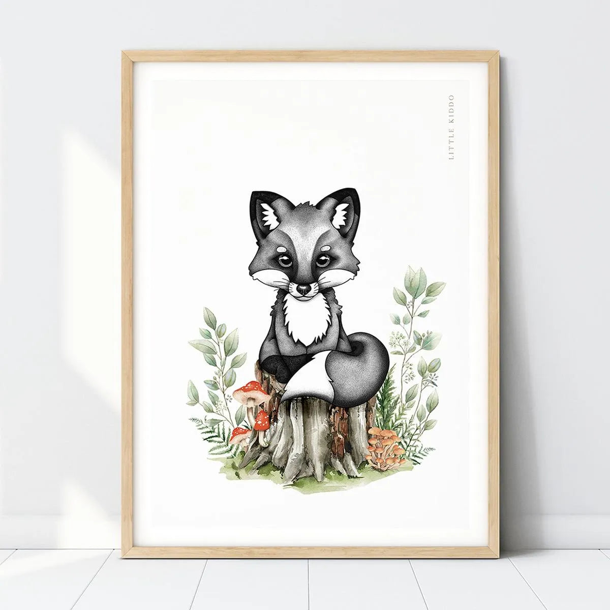 Hand-drawn baby fox nursery art print sitting on a tree stump with mushrooms and green leaves in a light wood frame, woodland forest wall decor.