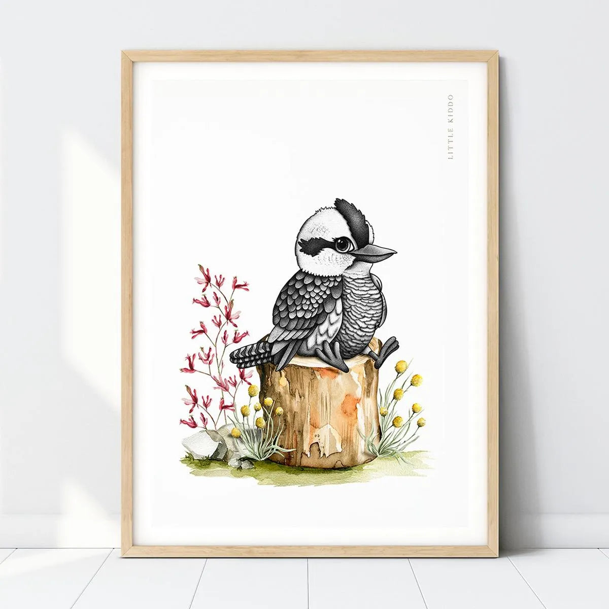 Hand-drawn baby Kookaburra nursery art print perched on a wooden stump with red kangaroo paw flowers in a light wood frame.