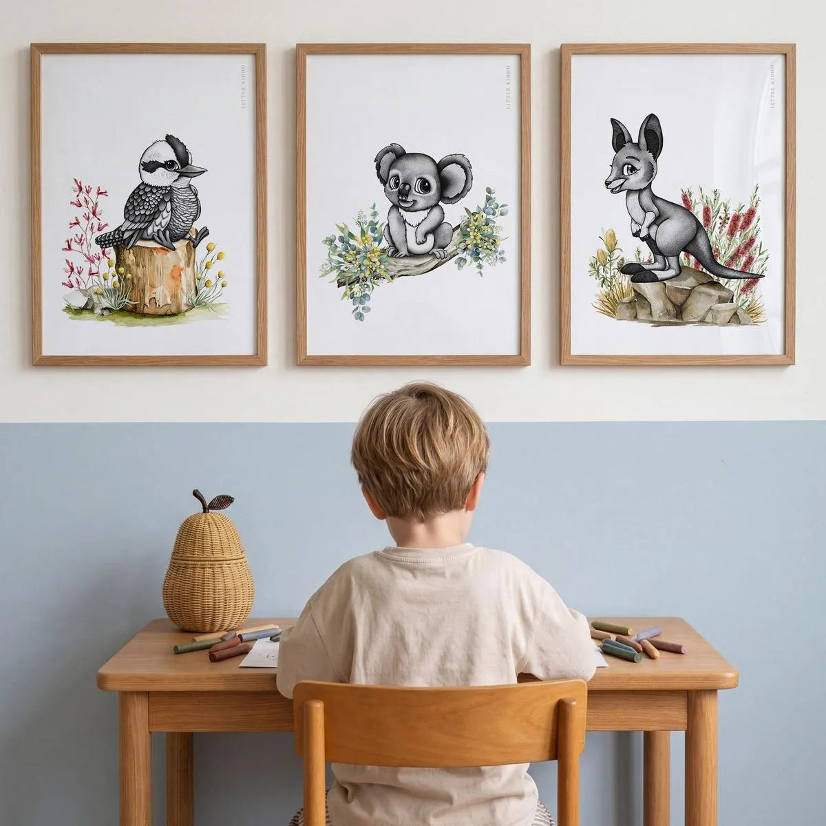 Set of 3 Australiana nursery prints—Kookaburra, Koala, and Kangaroo—styled in oak frames above a child's wooden study desk.
