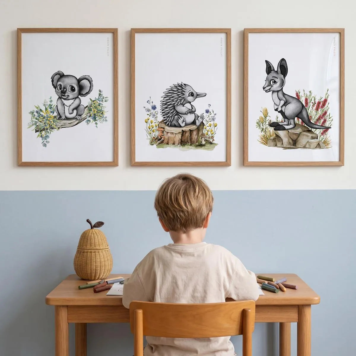 Set of 3 Australiana nursery prints—koala, echidna, and kangaroo—styled in oak frames above a child's wooden study desk.
