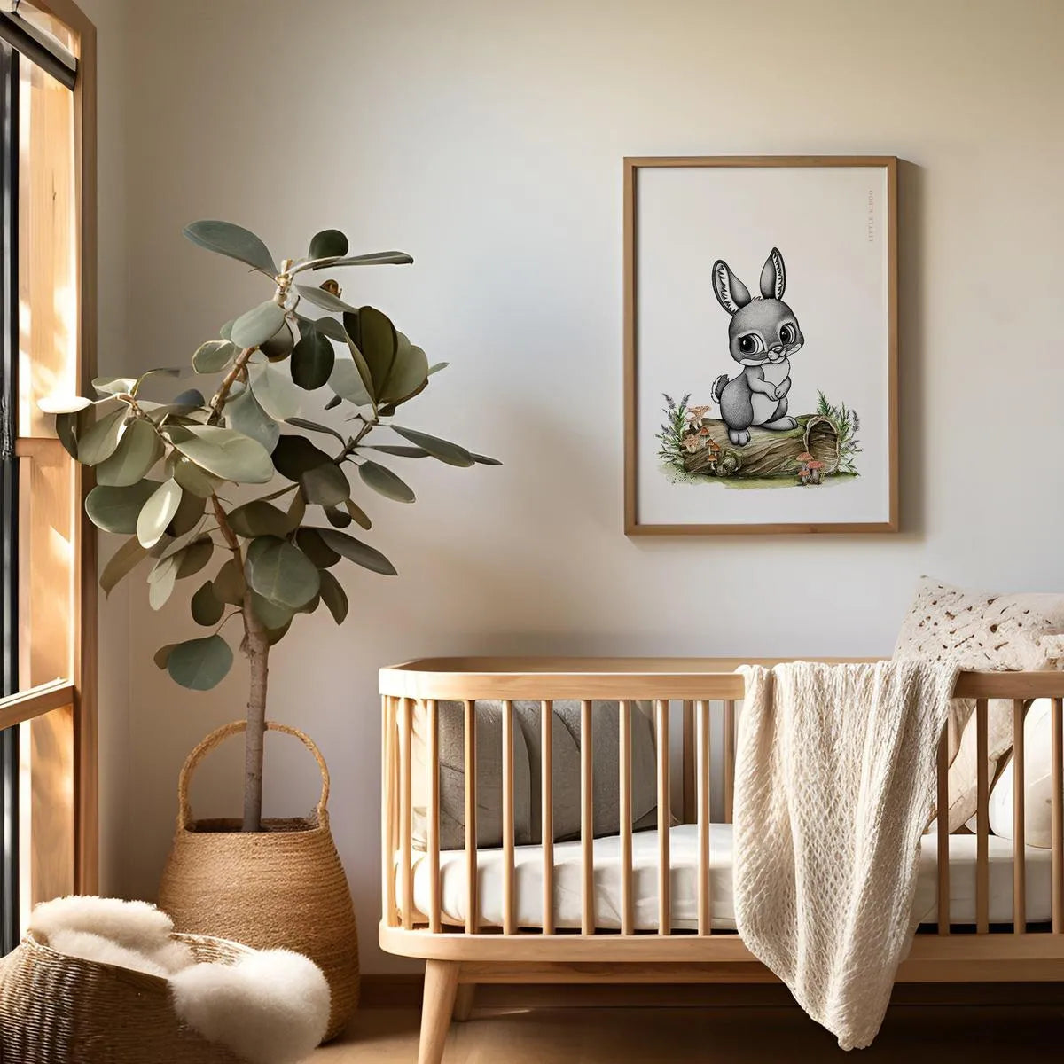 Modern woodland-themed nursery featuring a framed bunny-rabbit art print above a light wood crib with neutral decor.