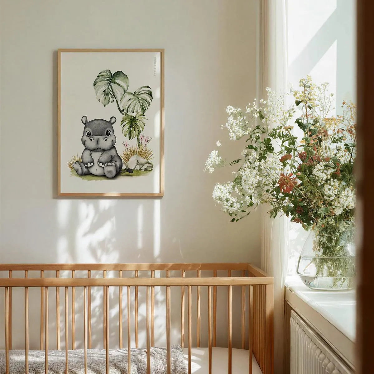 Whimsical hippo nursery wall art hanging above a wooden baby crib, gender-neutral safari animal decor in a bright nursery.
