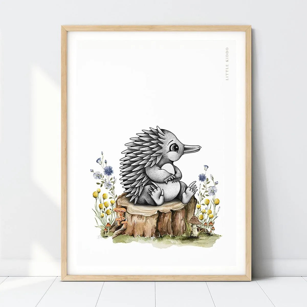 Hand-drawn baby echidna nursery art print sitting on a tree stump with yellow and blue wildflowers in a light wood frame.