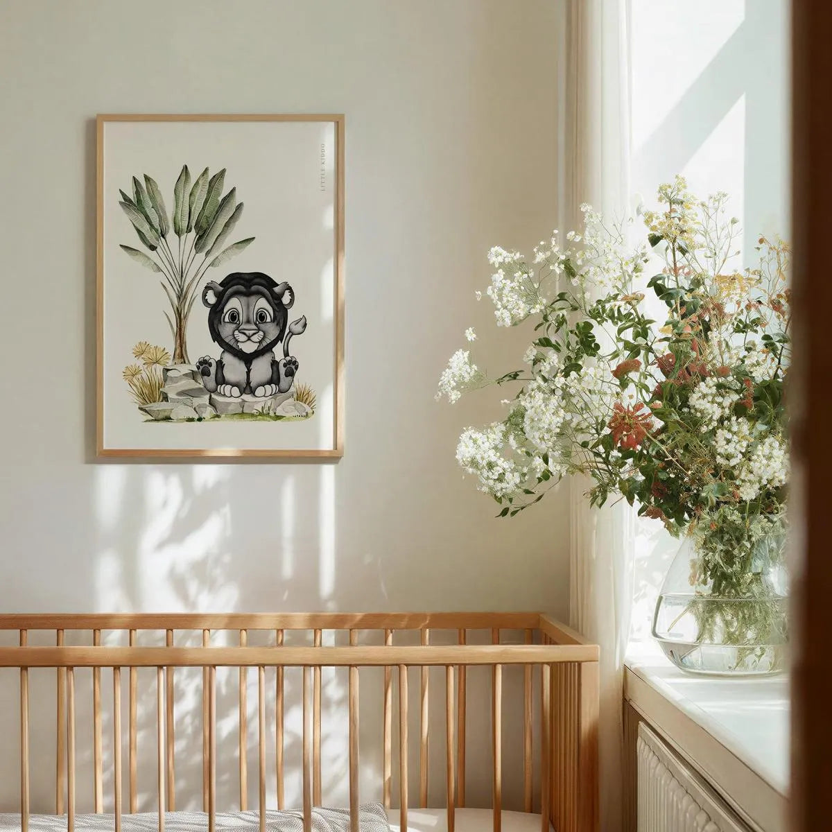 Whimsical lion cub nursery wall art hanging above a wooden baby crib, minimalist safari animal decor in a bright baby room.