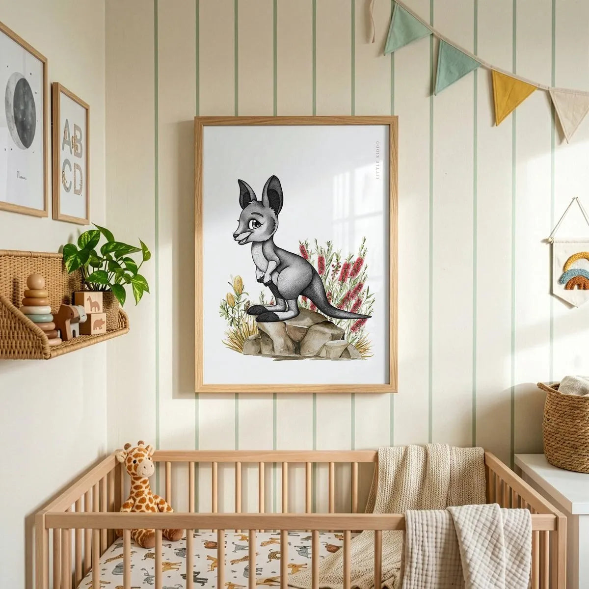 Minimalist baby kangaroo art hanging above a wooden crib in a nursery with striped wallpaper and colorful fabric bunting.