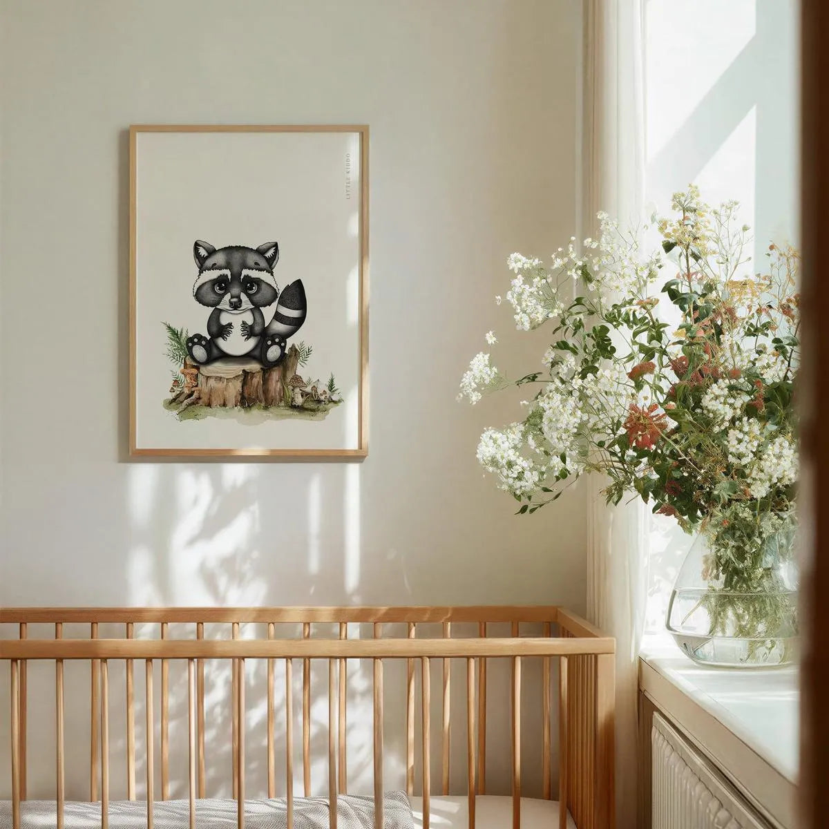 Minimalist baby raccoon art hanging above a wooden baby crib, gender-neutral woodland animal wall decor in a bright nursery.