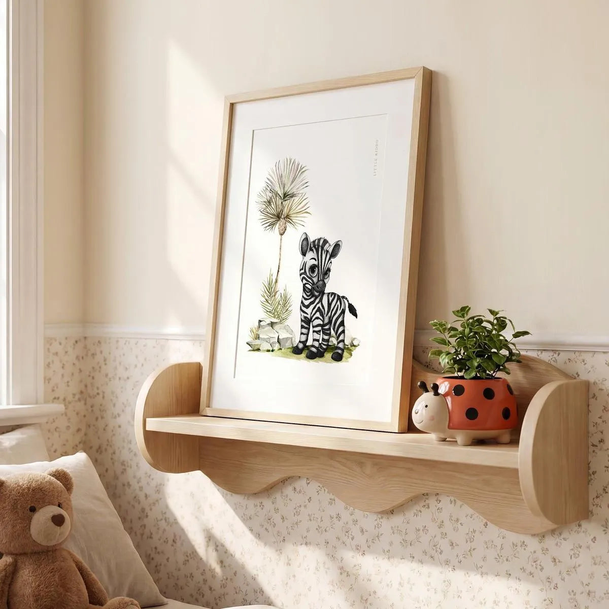 Framed zebra illustration sitting on a wooden nursery shelf, cute safari-themed bedroom decor and nursery styling ideas.