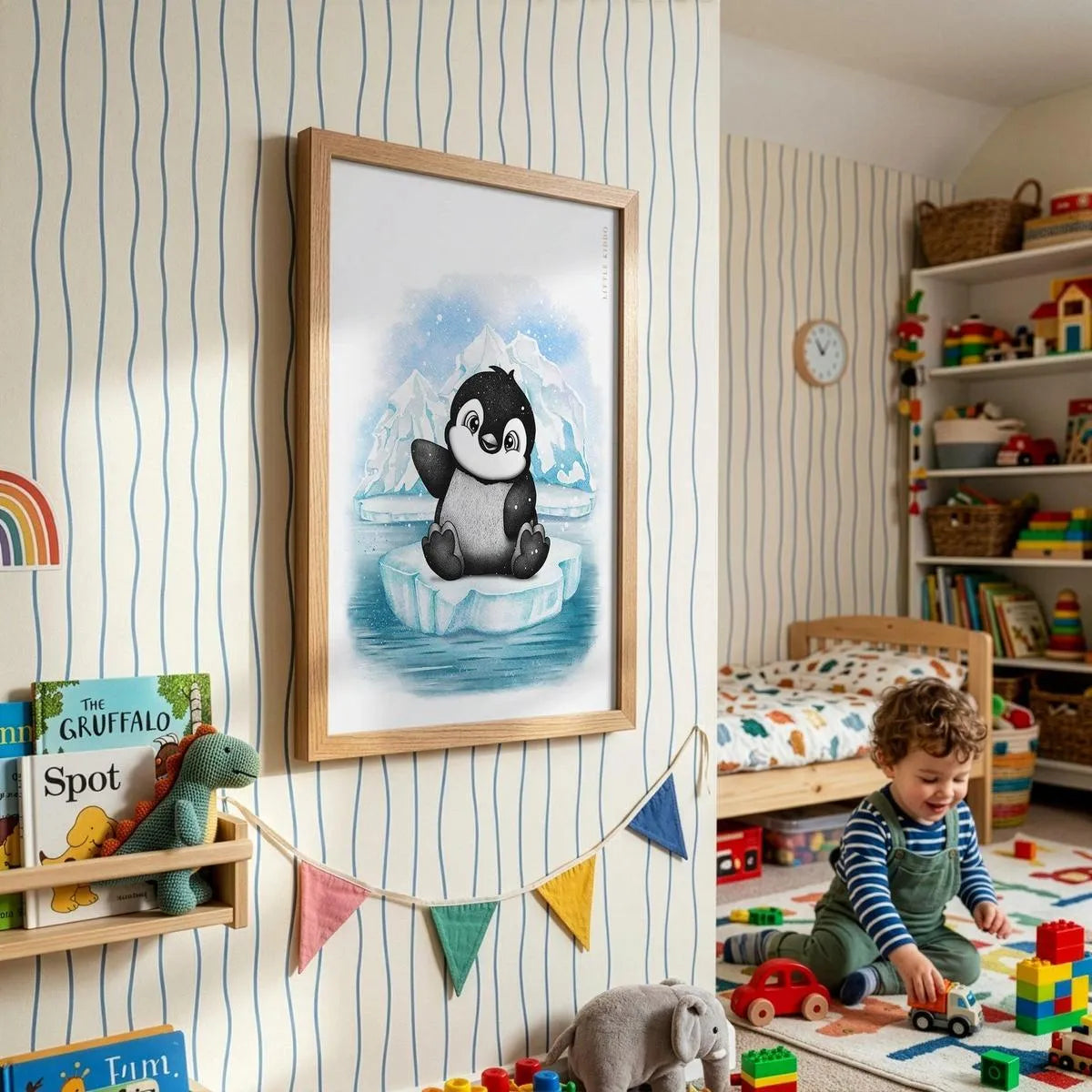 Framed penguin illustration on striped wallpaper in a colourful toddler playroom with rainbow bunting and wooden toys