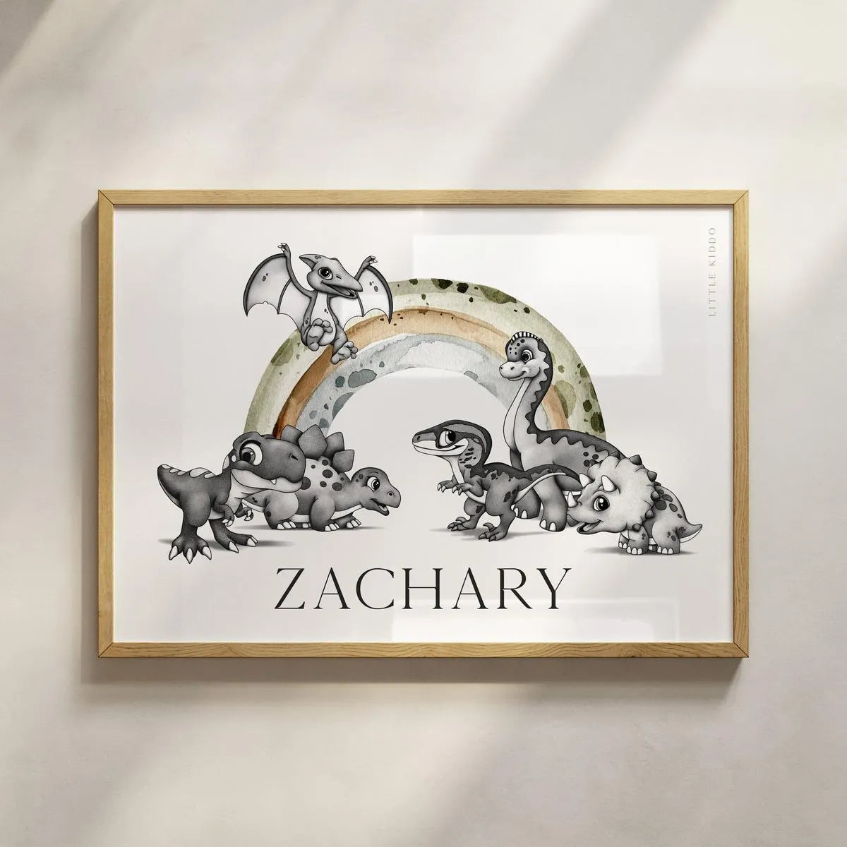 Personalized "Zachary" dinosaur nursery wall art in a light wood frame, minimalist prehistoric name sign for a boy's bedroom.