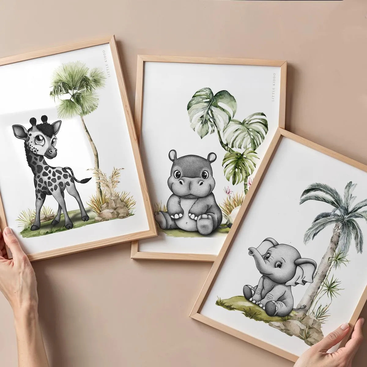 A curated collection of three safari-themed prints including a giraffe, hippo, and elephant in oak frames.