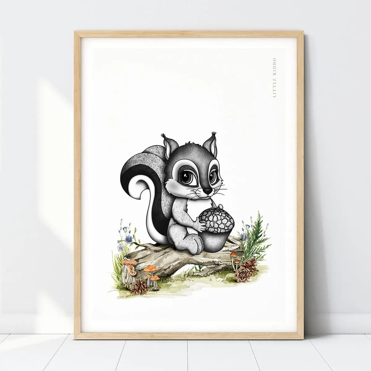 Hand-drawn baby squirrel nursery art print holding an acorn on a mossy log in a light wood frame, woodland forest wall decor.