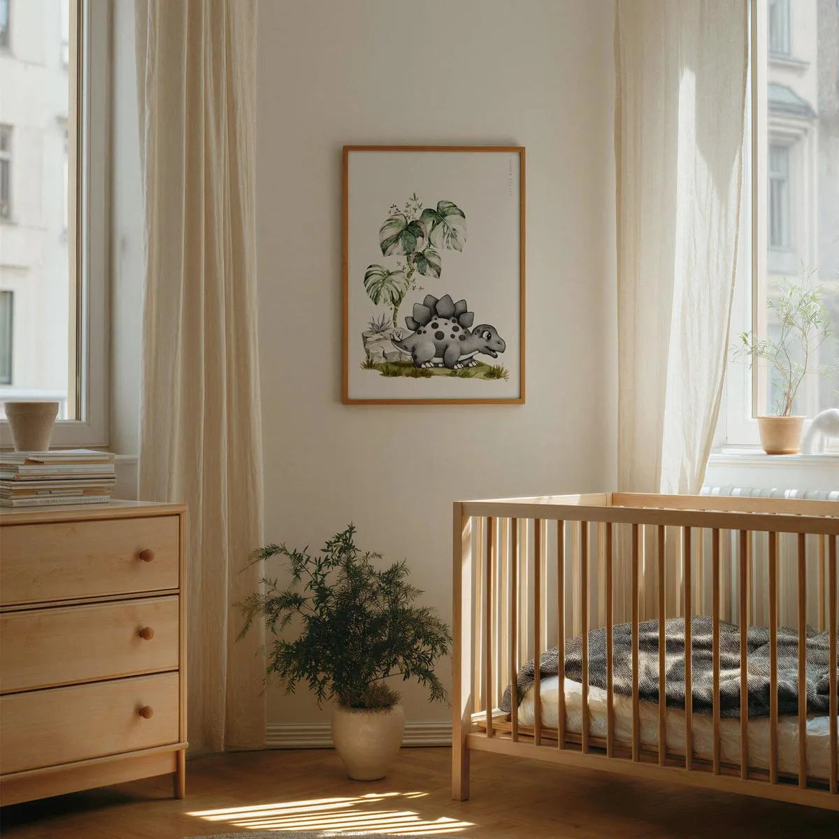 Hand-drawn Stegosaurus nursery art print in a light wood frame hanging on a beige wall above a matching light wood baby crib in a minimalist, sunlit nursery.
