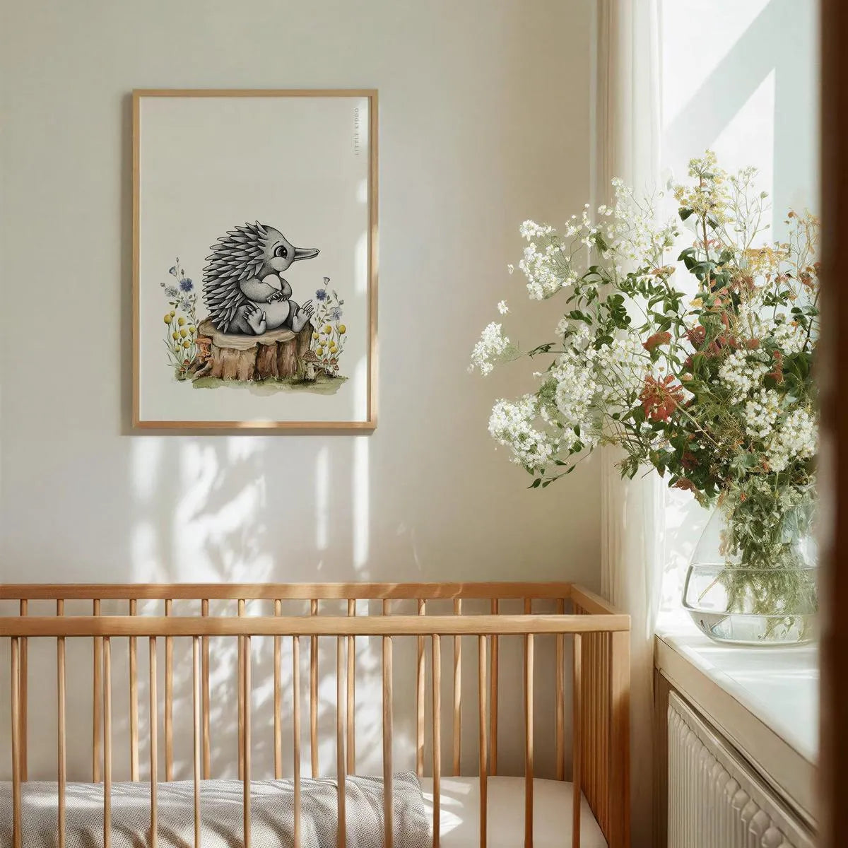 Whimsical baby echidna wall art hanging above a wooden crib, styled with fresh white flowers and neutral decor in a sun-drenched nursery.