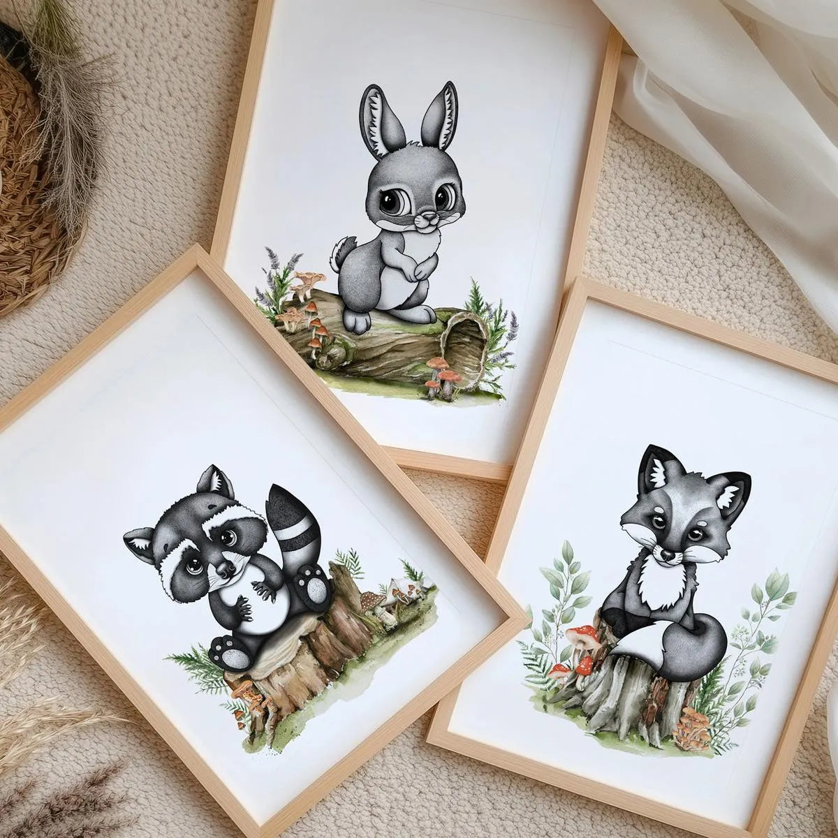 A curated collection of three woodland-themed nursery prints featuring a baby bunny rabbit, raccoon, and fox in matching oak frames, displayed on a textured neutral rug.